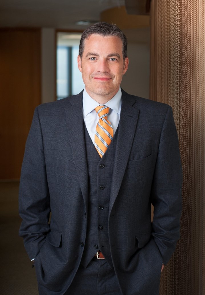 A professional portrait of attorney, Chris Moreland. He's wearing a suit, standing in a professional setting. 