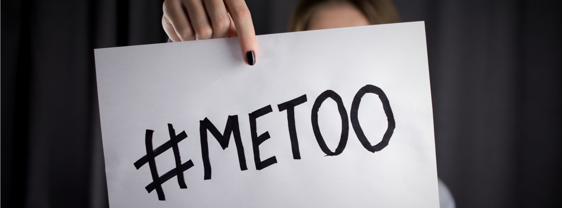 A close up shot of a paper reading "#Metoo" held by a woman whose features are hidden from view by the message. 