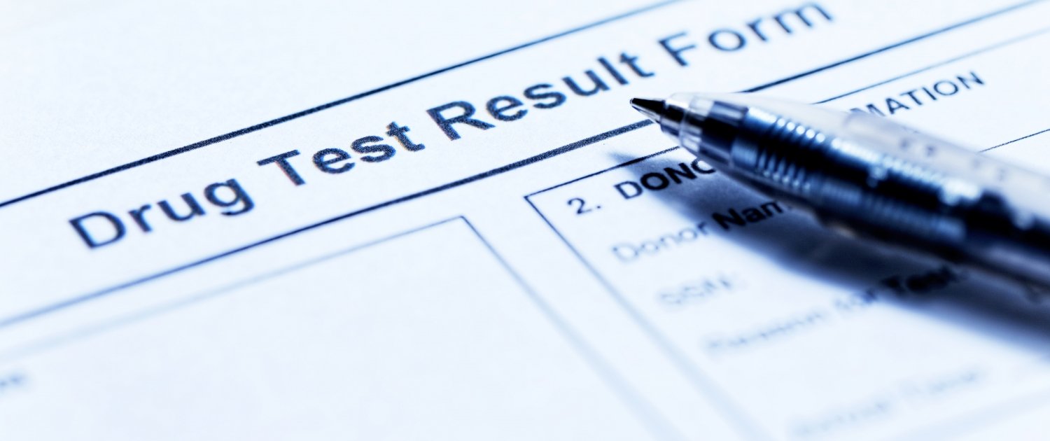 A photo of a document reading "Drug Test Result Form". A black ballpoint pens rests on the document.