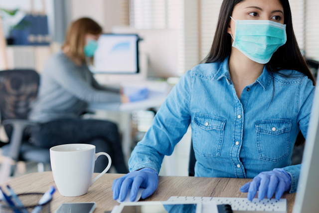 Woman-at-compter-wearing-gloves-and-a-mask-for-Covid-protection