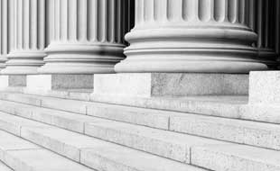 Black and white photo of pillars and steps in front of a courthouse