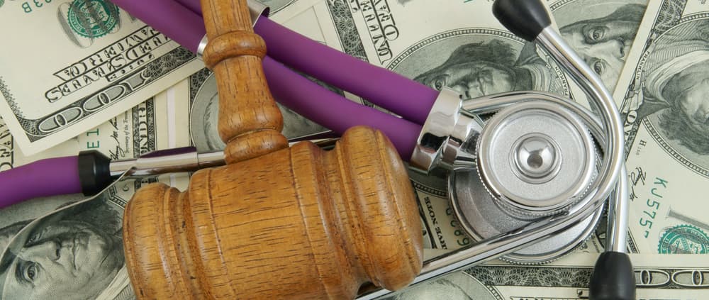 gavel and stethoscope on a pile of money
