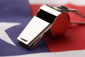 A silver whistle, reflecting light, rests on the red and white stripes of the American flag. 