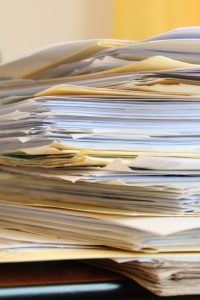 Photo of a tall stack of documents with a warmly colored background.