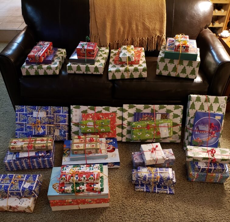 Stacks of neatly wrapped Christmas presents rest on a living room couch and on the floor. 