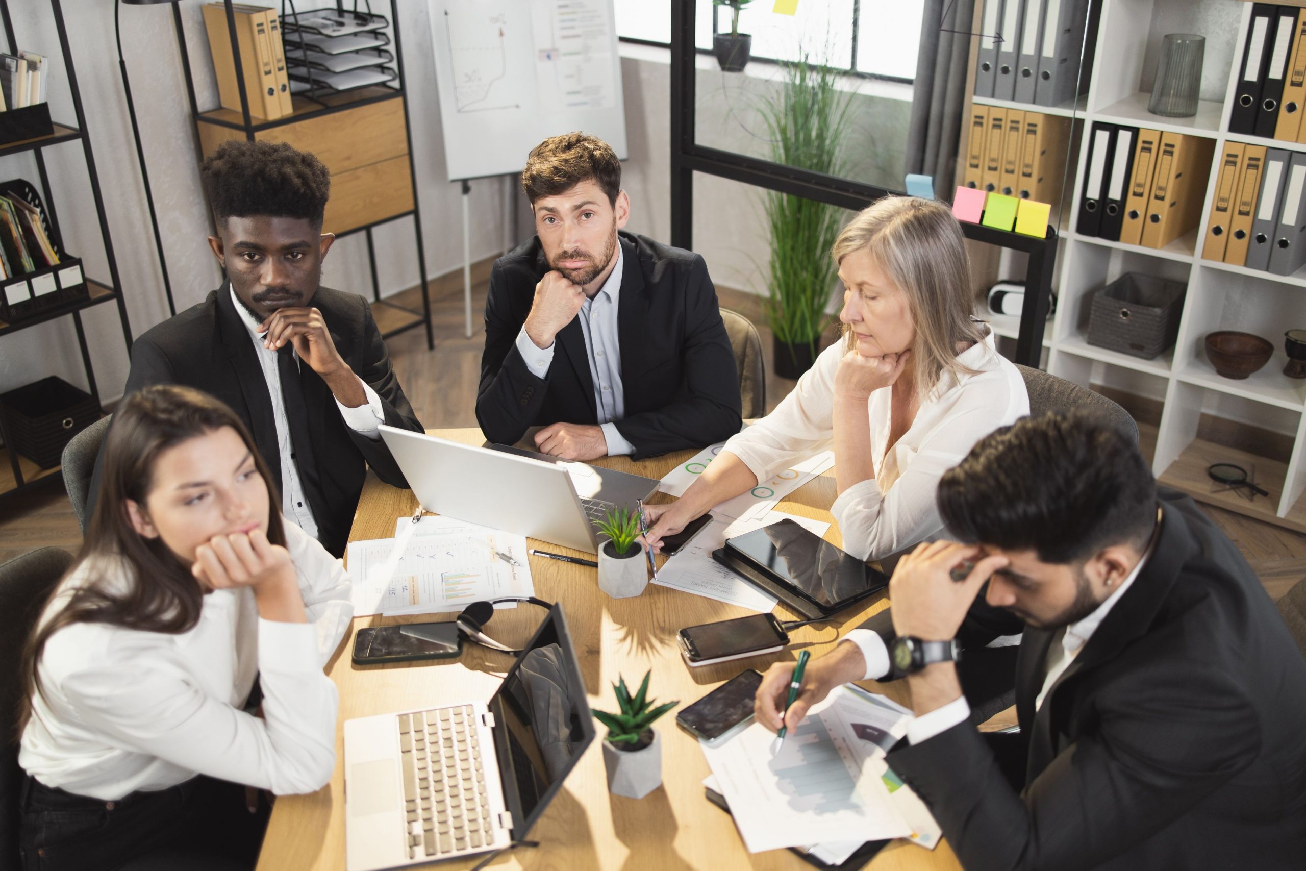 bored colleagues with laptops on desk sitting in office