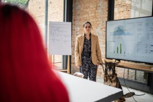 Visually impaired businesswoman doing a presentation in a business meeting with guide dog