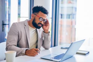 Shot of a young businessman suffering from a headache in a modern office at work