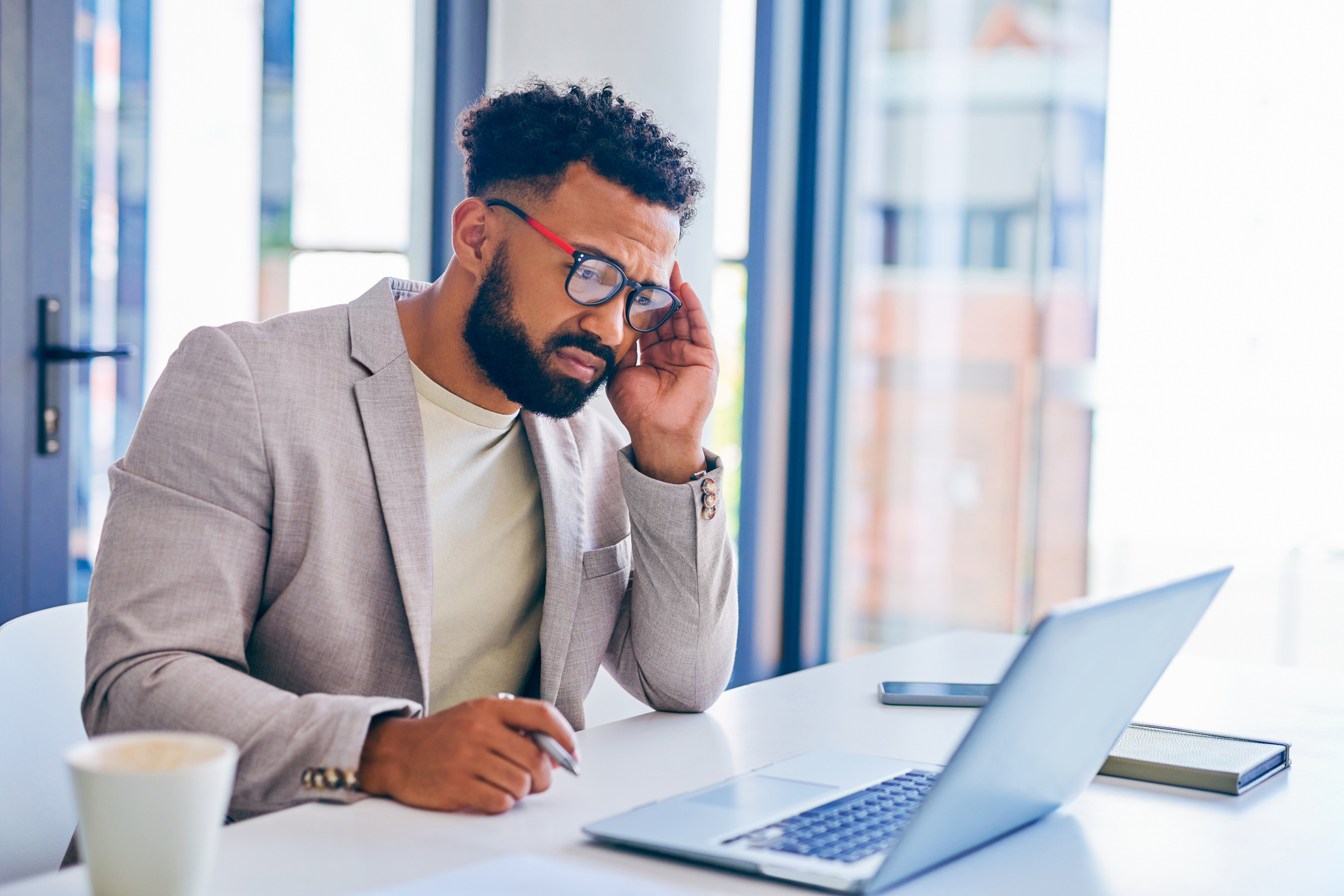 Shot of a young businessman suffering from a headache in a modern office at work